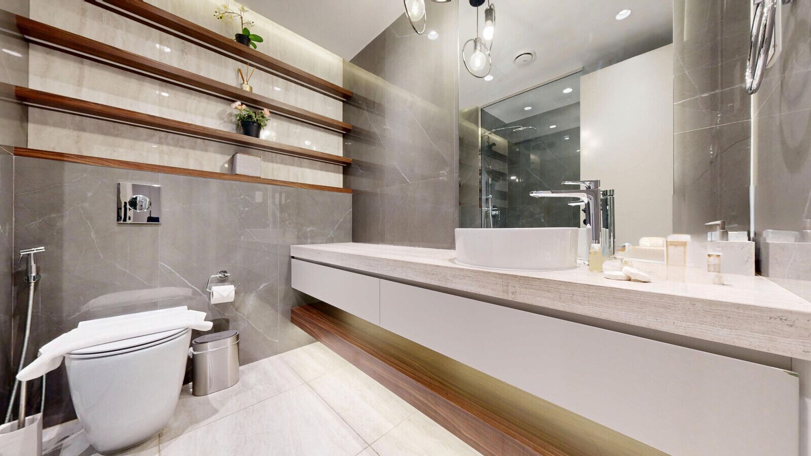 Een moderne badkamer met een grote spiegel, een witte wastafel en een toilet.