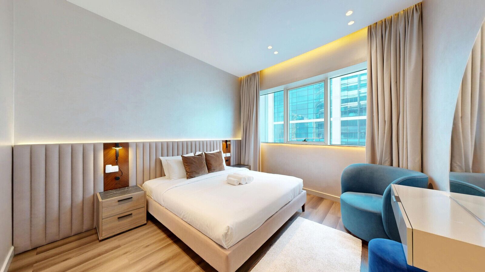 Een moderne hotelkamer met een groot bed, nachtkastjes, een bureau en een stoel.