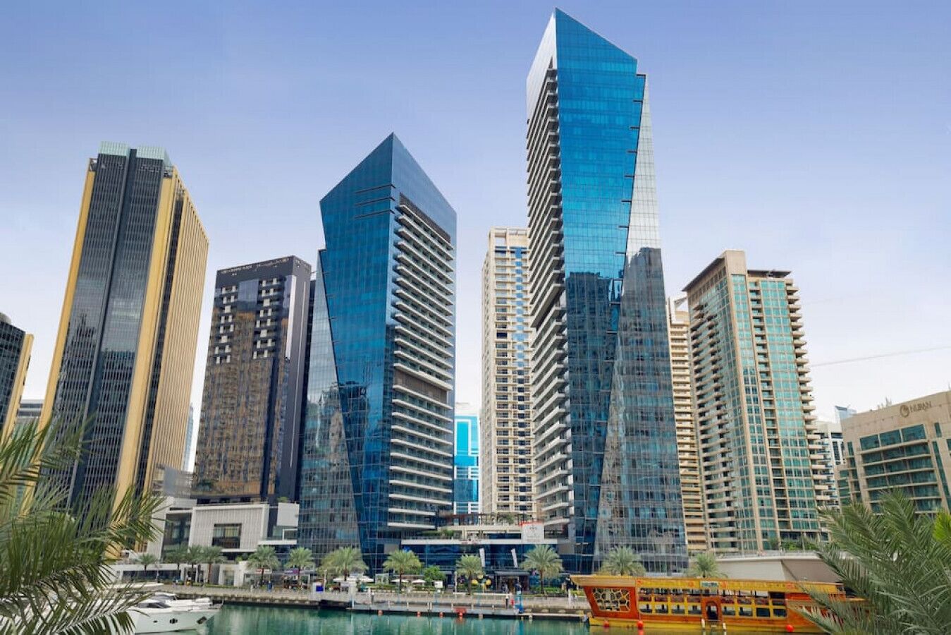 A cityscape with modern high-rise buildings, a waterfront, and a bus stop.