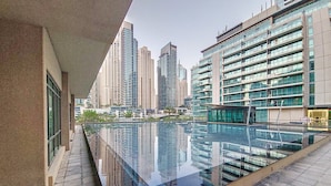 Een modern gebouw met een reflecterend zwembad en hoge gebouwen op de achtergrond.