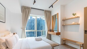Een moderne slaapkamer met een groot bed, uitzicht op hoge gebouwen en inbouwplanken.