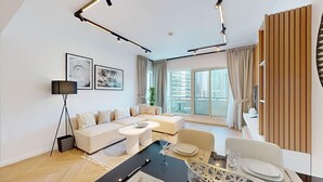 Een moderne woonkamer met een bank, een eettafel en grote ramen met uitzicht op de stad.