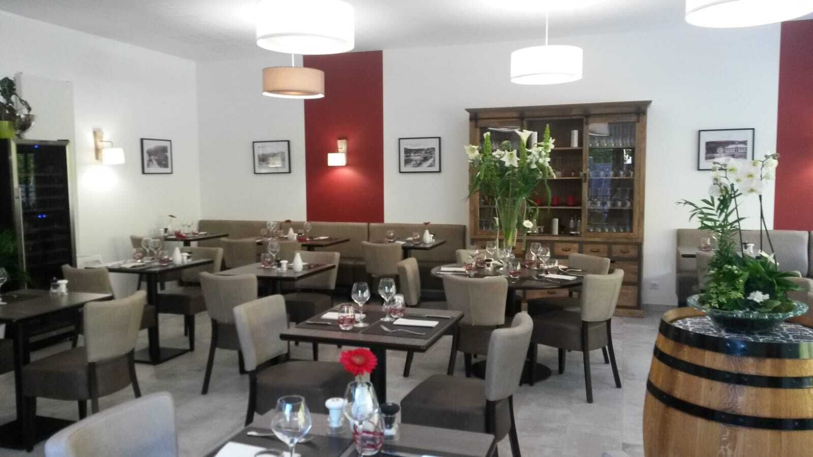 A restaurant with multiple tables and chairs, a bar area, and a bookshelf in the background.