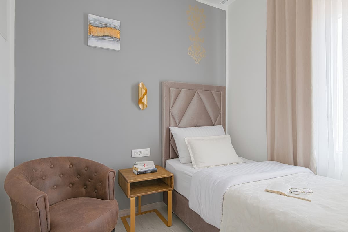 Un dormitori amb un llit, una tauleta de nit, una cadira i una decoració mural.