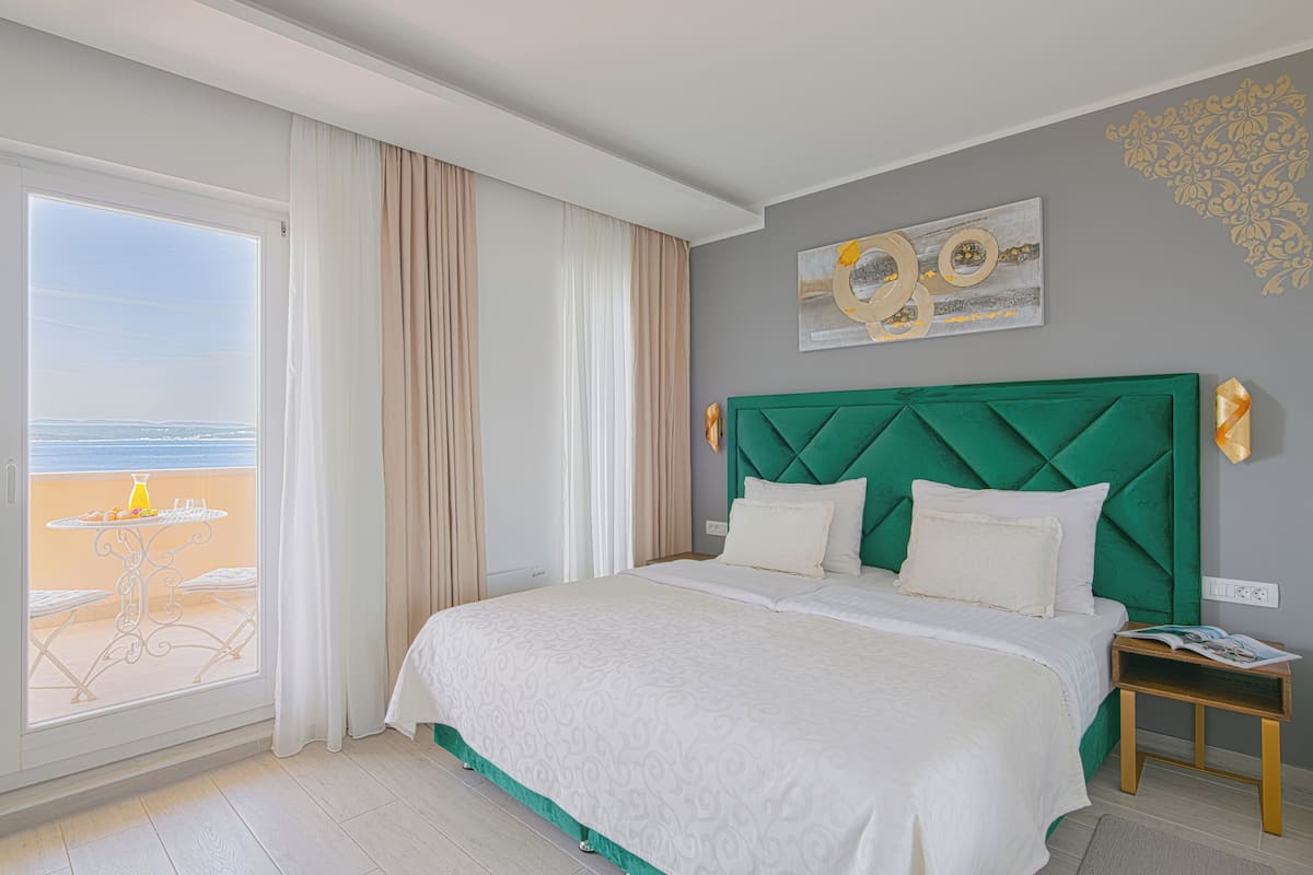 Habitació d'hotel amb un llit gran, vistes a la platja i una taula amb seients exteriors.