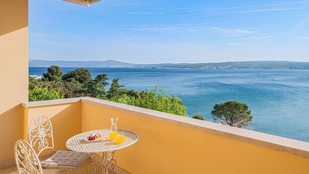 Un balcon avec une table dressée pour deux personnes, offrant une vue panoramique sur la côte.