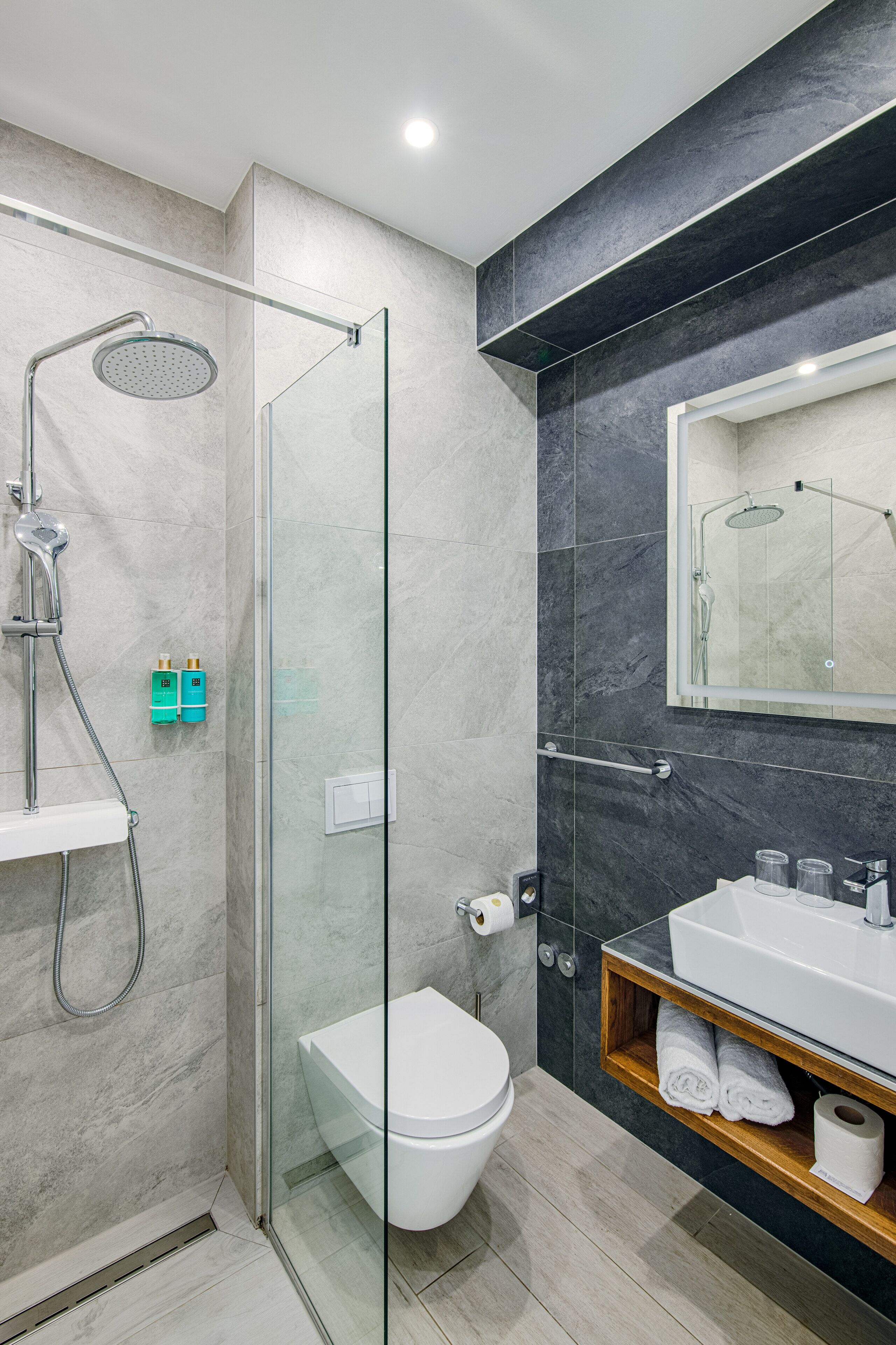 Un baño moderno con ducha envuelta en vidrio, inodoro blanco y tocador con espejo.