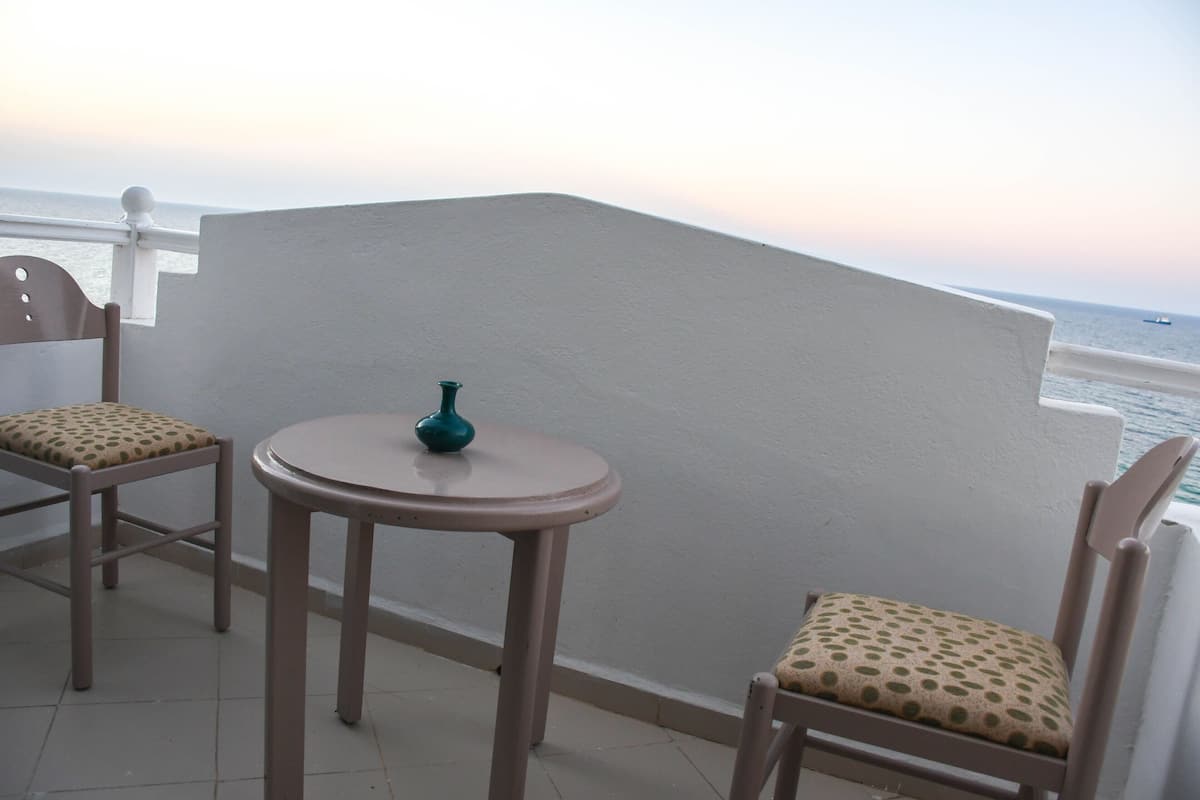 A balcony with two chairs and a small table, overlooking a body of water.