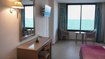Habitación de hotel con cama, escritorio, silla, televisión y vista al mar.