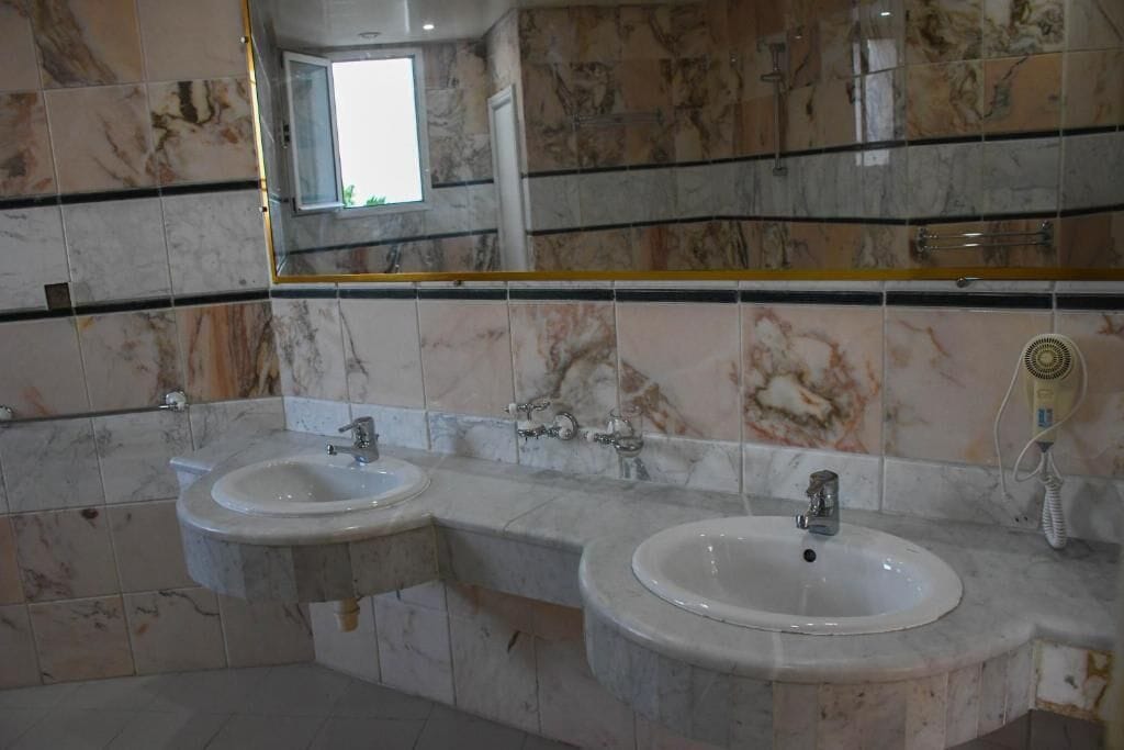 Une salle de bain avec deux lavabos, des carreaux de marbre et un miroir.