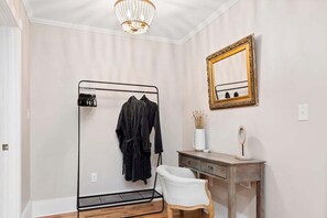 A room with a metal rack holding clothes, a wooden vanity with a mirror, and a white chair. - 7 Miles to DT AVL, Hot Tub, Mountain View, Fenced (Fairview)