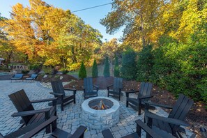 Relax by the fire pit surrounded by lush greenery and trees.
