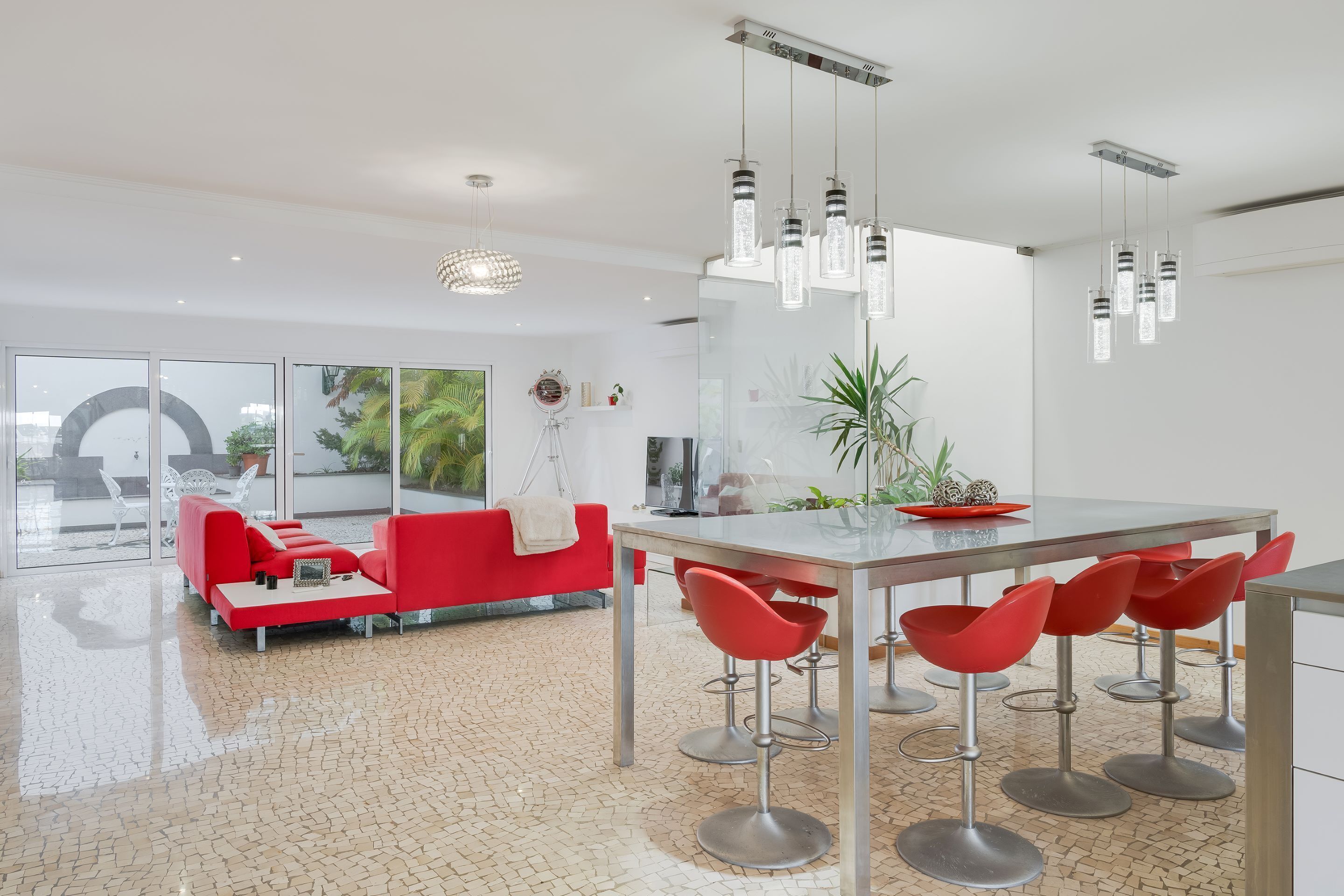 Una cocina moderna con una isla central, taburetes rojos y luces colgantes.
