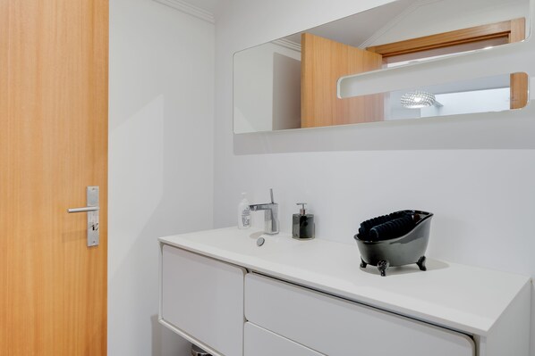 Une salle de bain moderne avec un meuble-lavabo blanc, une baignoire noire et un miroir au-dessus du lavabo.