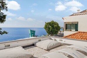 Une terrasse avec des fauteuils de jardin blancs et une vue sur la mer.