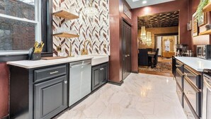 A modern kitchen with a herringbone-patterned backsplash, built-in appliances, and a large window.