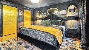 A bedroom with a bed, bedside tables, a mirror, and a wardrobe. - The Prohibition -Uniquely Designed Midtown Stunner (Kansas City)