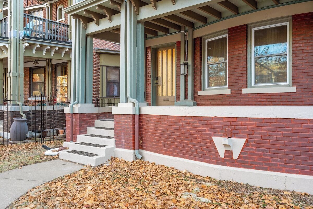 A red brick building with white trim, a front porch, and a staircase leading to the entrance.