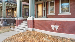 A red brick building with white trim, a front porch, and a staircase leading to the entrance.