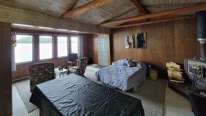 Una cabaña con dos camas, una chimenea, un televisor y una ventana con vista a un lago.