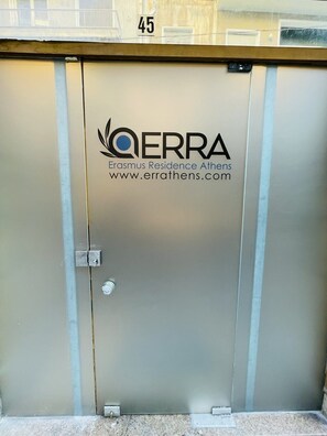 Een metalen deur met het logo en de naam 'QERRA' en de website 'www.errathens.com'.