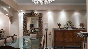 A dining area with a glass table, ornate chairs, a large mirror, and a wooden cabinet. - Vesta - Mokattam Residence (Cairo)