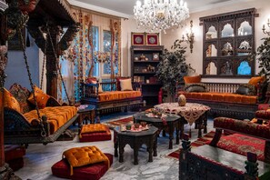 Una habitación ricamente decorada con muebles ornamentados, un candelabro y un espejo grande.