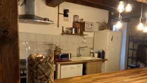 A kitchen with a wooden countertop, a glass jar filled with wine corks, a sink, and a refrigerator. - The vacation home (Siorac-de-Ribérac)