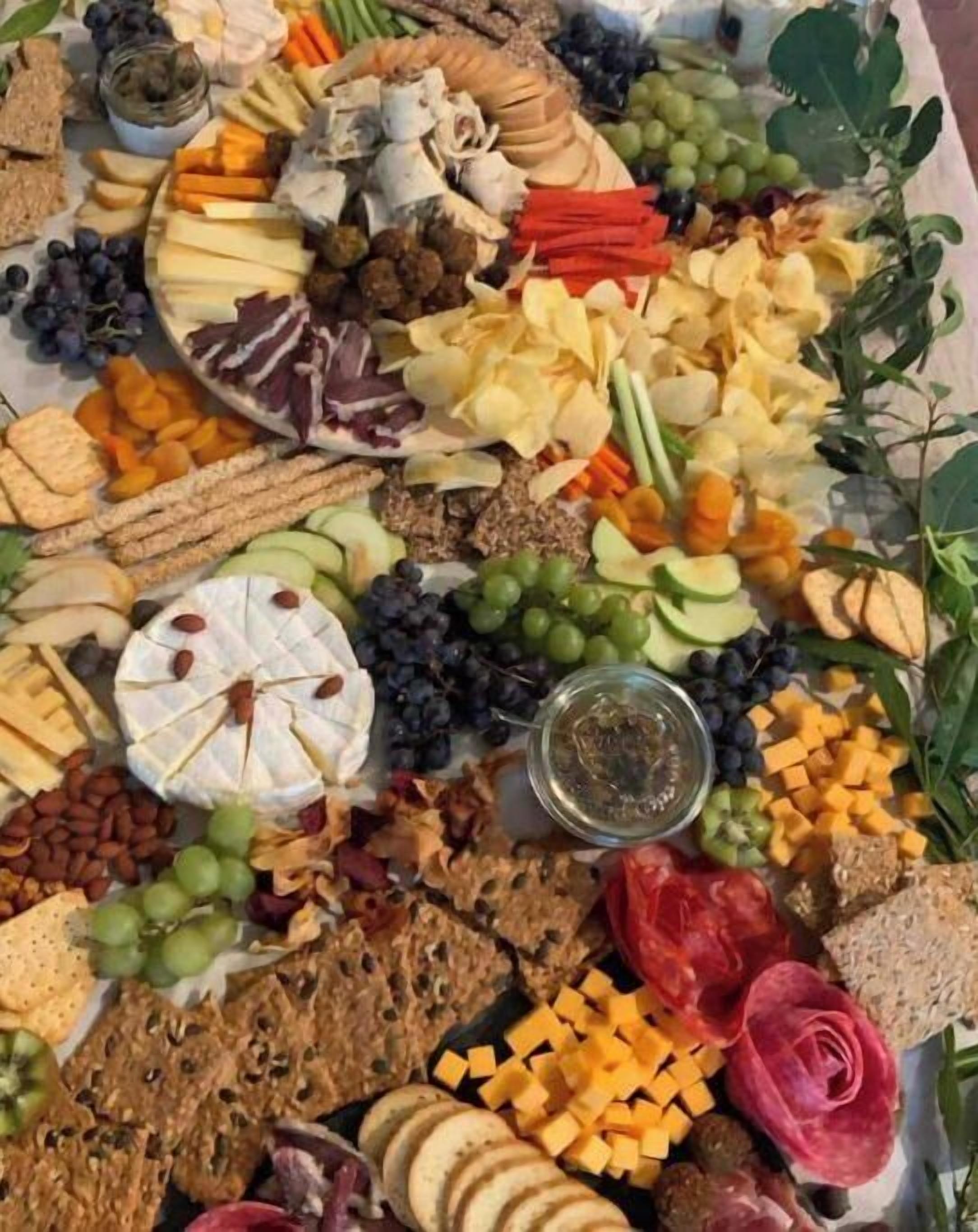A charcuterie board with various cheeses, fruits, nuts, and crackers.
