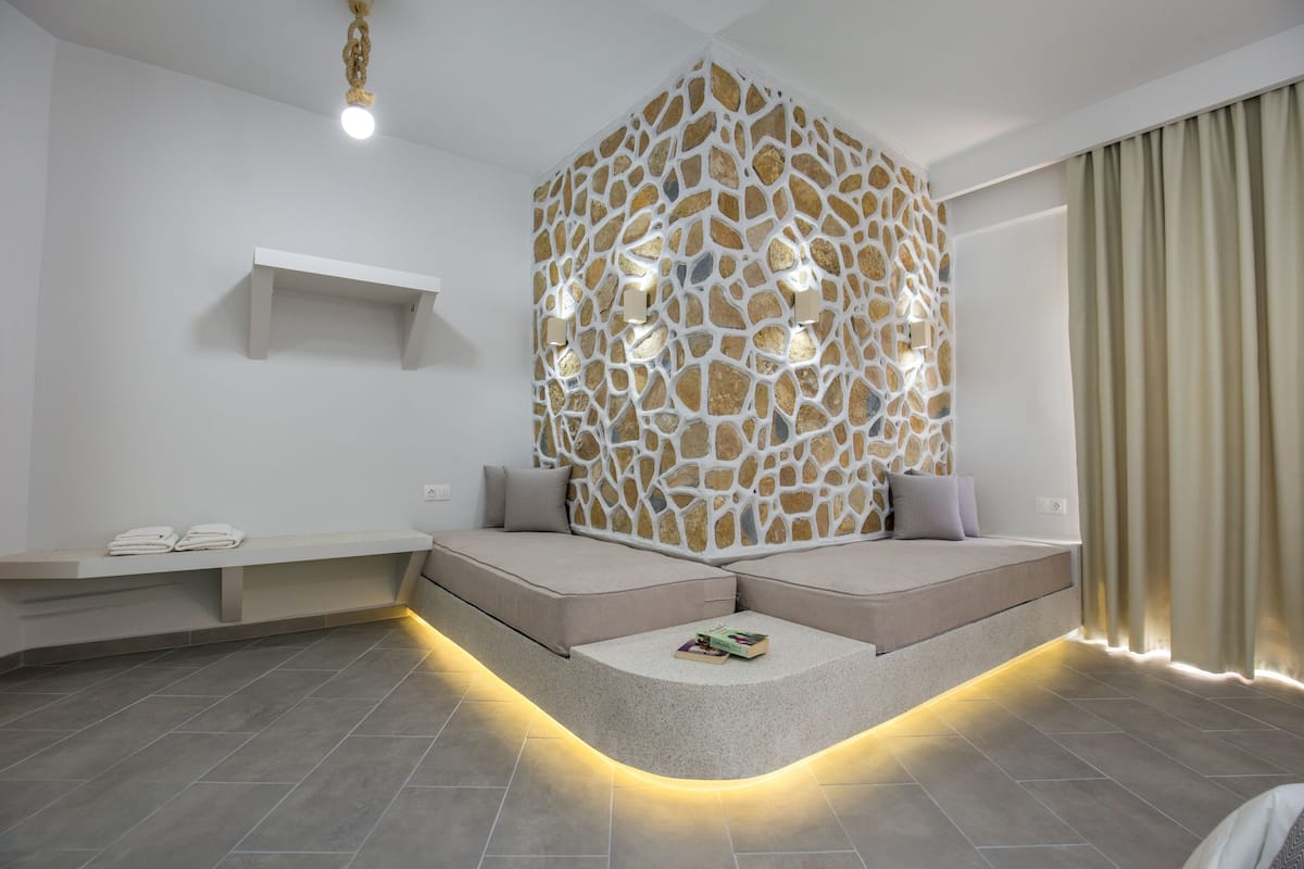 A modern room with a built-in seating area, a stone-patterned wall, and a shelf with towels.