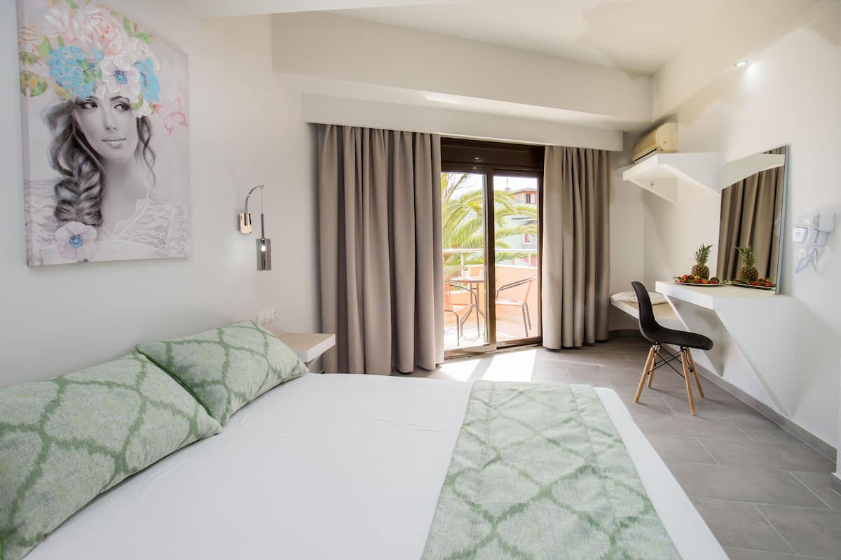 A modern hotel room with a large bed, a desk, and a view of the outdoor area.