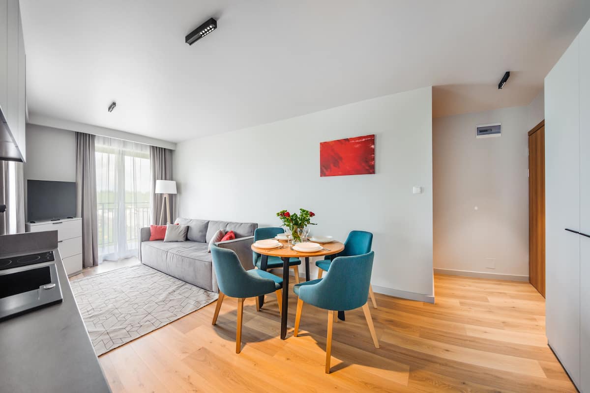 Uma sala de estar moderna com área de refeições, um sofá, uma TV e uma cozinha.