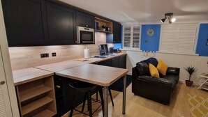 A compact living space with a kitchenette, a dining area, a sofa, and a TV. - Hayling Hideaway, private self contained cosy annex near to beach (Hayling Island)