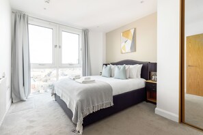 Une chambre avec un grand lit, une table de chevet, une fenêtre avec des rideaux et une vue sur la ville.
