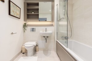 Une salle de bain moderne équipée de toilettes, d’un lavabo et d’une douche à parois de verre.