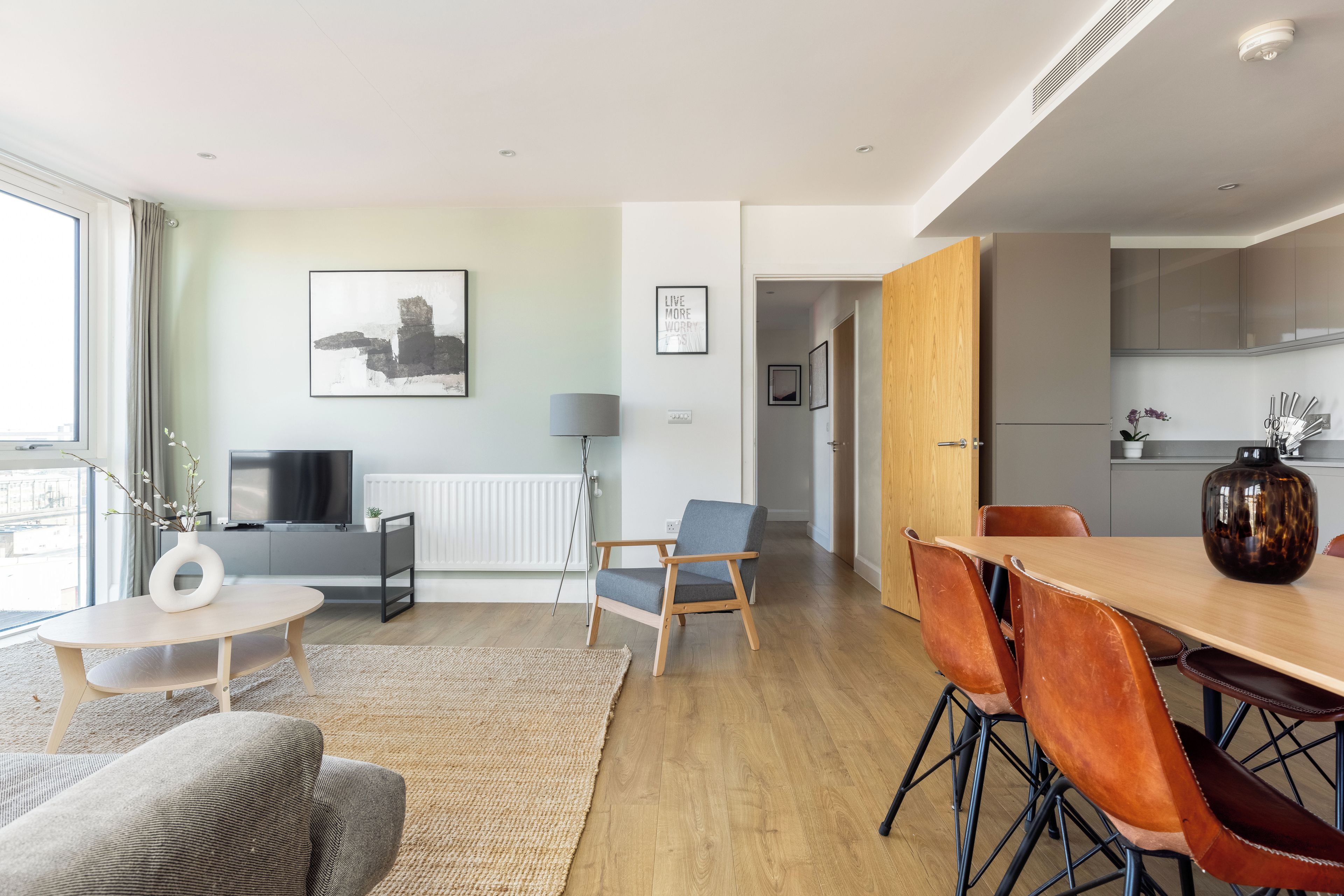 Uma sala de estar moderna com sofá, mesa de centro e área de jantar com cadeiras e mesa.