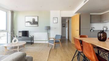 Uma sala de estar moderna com sofá, mesa de centro e área de jantar com cadeiras e mesa.