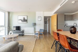Uma sala de estar moderna com sofá, mesa de centro e área de jantar com cadeiras e mesa.