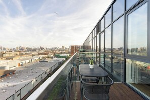 En balkon med udsigt over bybilledet, en potteplante og en metalstol.