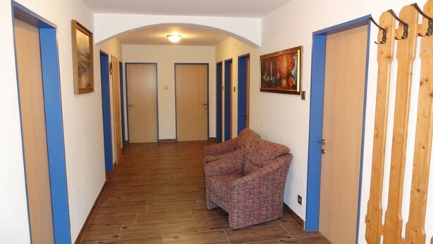 A hallway with wooden flooring, blue-framed doors, and a patterned armchair. - Appartement im 1.0g- - Urlaub auf dem Aignerhof (Muhr)