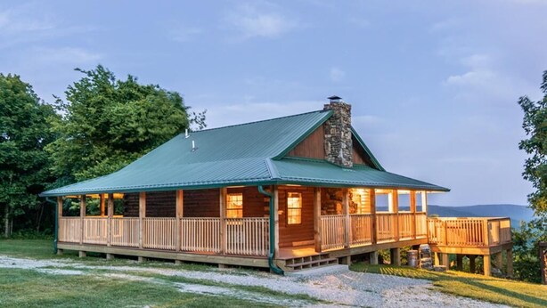 A lodge with a covered porch, a stone chimney, and a deck overlooking a body of water. - Buffalo River Cabin w/ Hot Tub (Ponca)