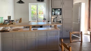 A kitchen with a wooden island, white cabinets, and a window with a view of greenery.