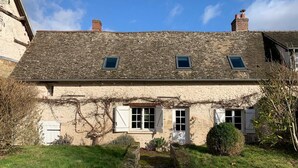 A traditional stone house with a sloped roof, two small windows, and a front door.