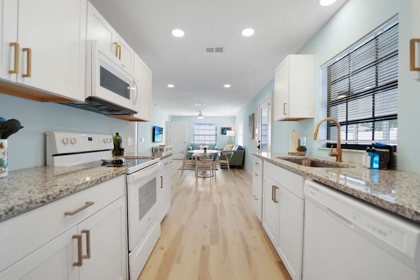 Una cocina moderna con armarios blancos, encimeras de granito y una isla central.