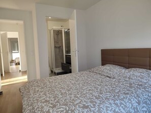 Une chambre à coucher comprenant un lit, un espace douche et un couloir menant à une autre pièce.