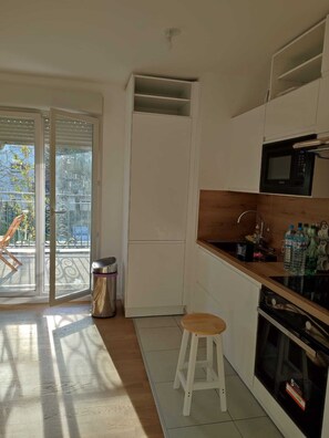 Une cuisine avec des meubles blancs, un four à micro-ondes et un plan de travail en bois.