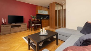 A modern living room with a grey sofa, a wooden coffee table, and a flat-screen TV on a wooden cabinet. - Climate Studio in Downtown | Smart TV | Center (Warszawa)