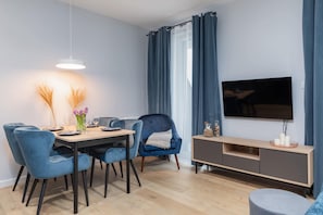 A modern dining area with a table, chairs, and a TV mounted on the wall.