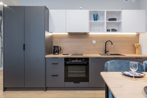 A compact kitchen with a built-in oven, a coffee maker, and a sink.