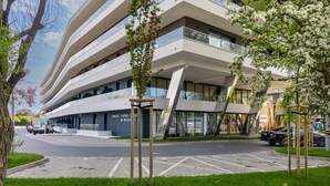 A modern multi-story building with a curved facade, a parking area, and a sign for a smart aging clinic.